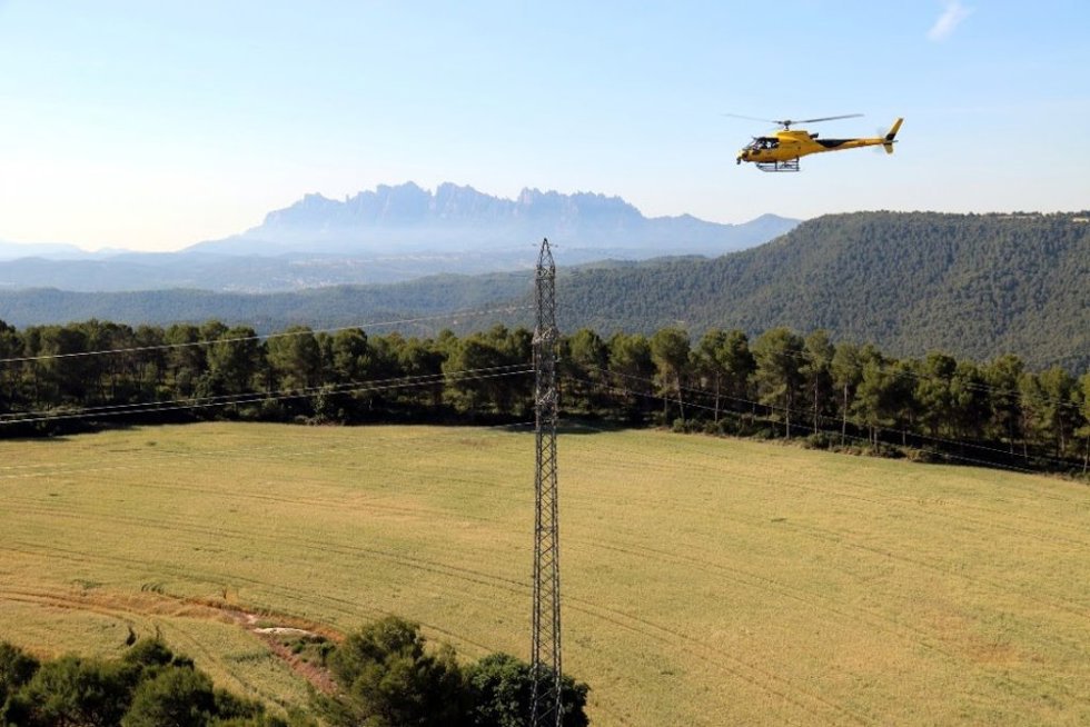 Imagen de un helicóptero sobrevolando una línea eléctrica.