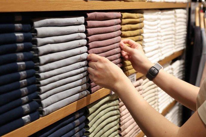 Archivo - Una dependienta colocando la ropa en un comercio textil