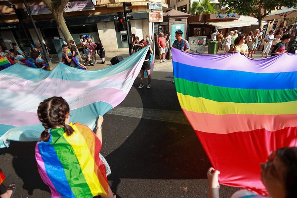 Archivo - Varias personas sujetan dos banderas del colectivo LGTBIQ.