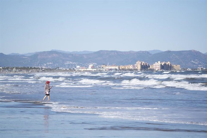Archivo - Una mujer moja los pies a la orilla de la playa de la Malvarrosa. 
