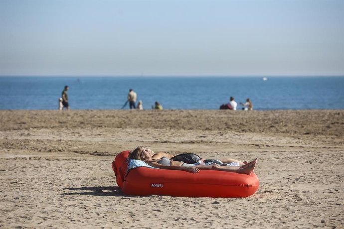 Archivo - Arxiu - Una dona pren el sol tombada en un flotador, en la platja de la Malvarrosa. 