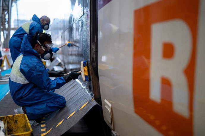 Operarios limpian grafitis en vagones de tren en la Estació de França de Barcelona