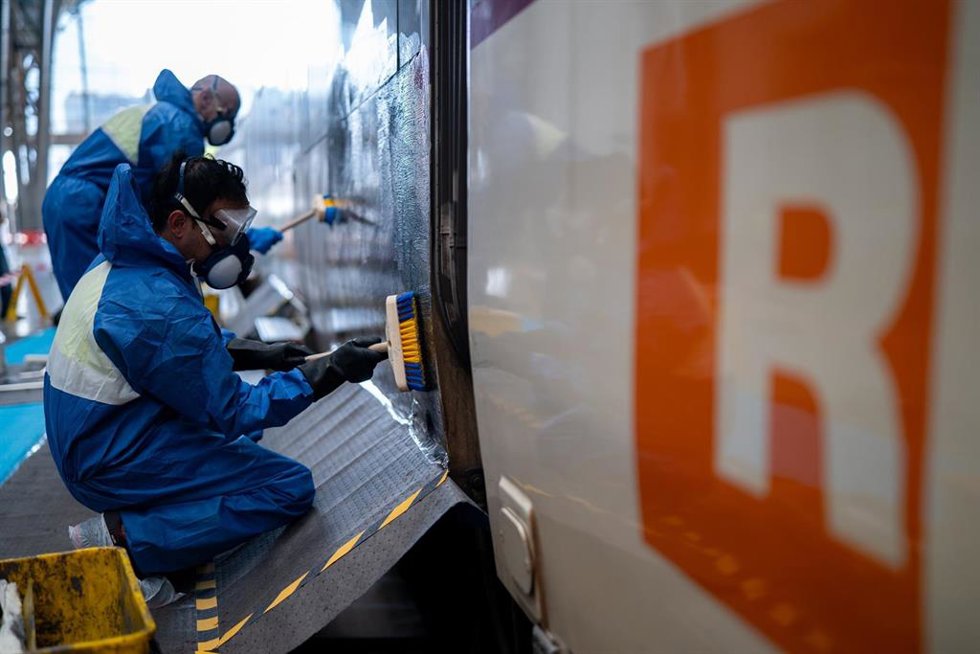 Operarios limpian grafitis en vagones de tren en la Estació de França de Barcelona