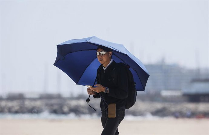 Archivo - Un hombre camina por la playa de la Malvarrosa. 