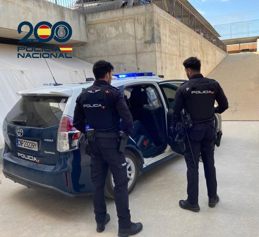 Archivo - Agentes de Policía junto a un coche patrulla.