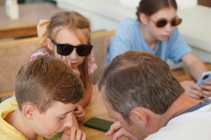 Padre e hijos usando un teléfono móvil
