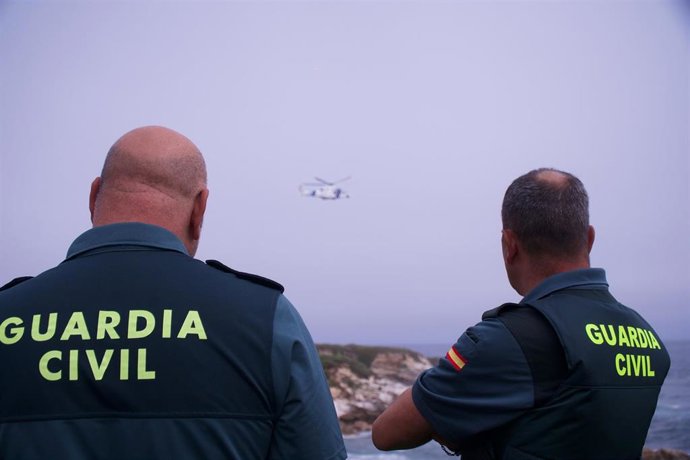 Archivo - Dos agentes de la Guardia Civil observan a un helicóptero.