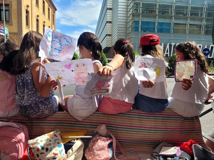 Un grupo de niñas enseñan los dibujos que le han pintado al Papa mientras esperaban al Papamóvil.