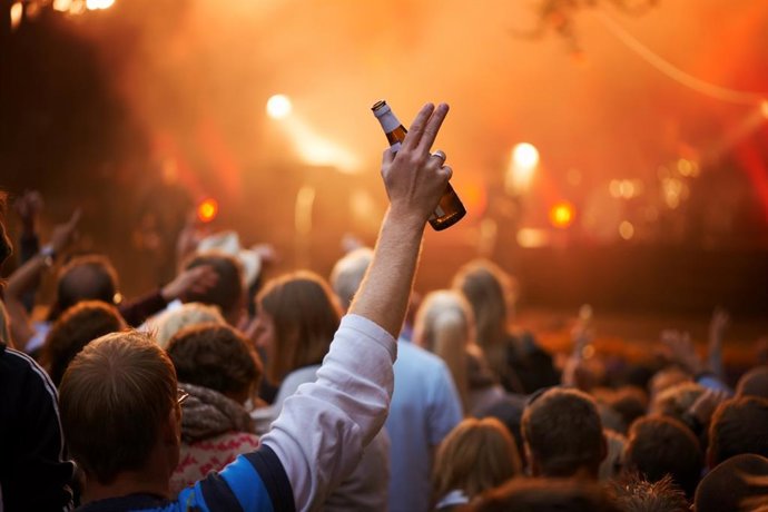 Archivo - Hombre bebiendo en un concierto, mano levantada