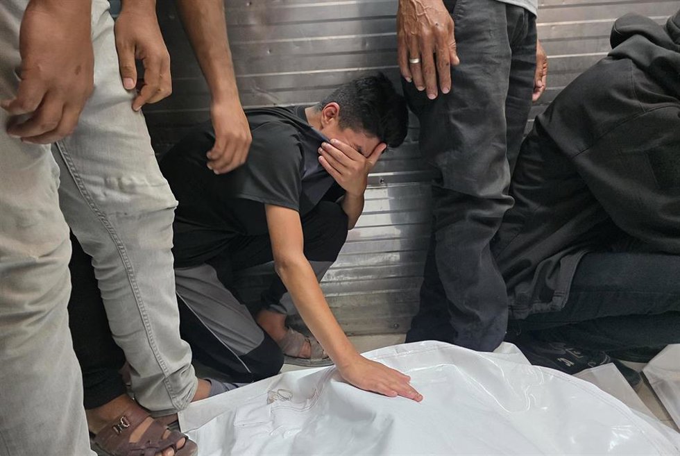 Palestinos junto a los cadáveres de dos personas muertas en un bombardeo de Israel contra el sur de la Franja de Gaza a pesar del alto el fuego pactado en octubre de 2025