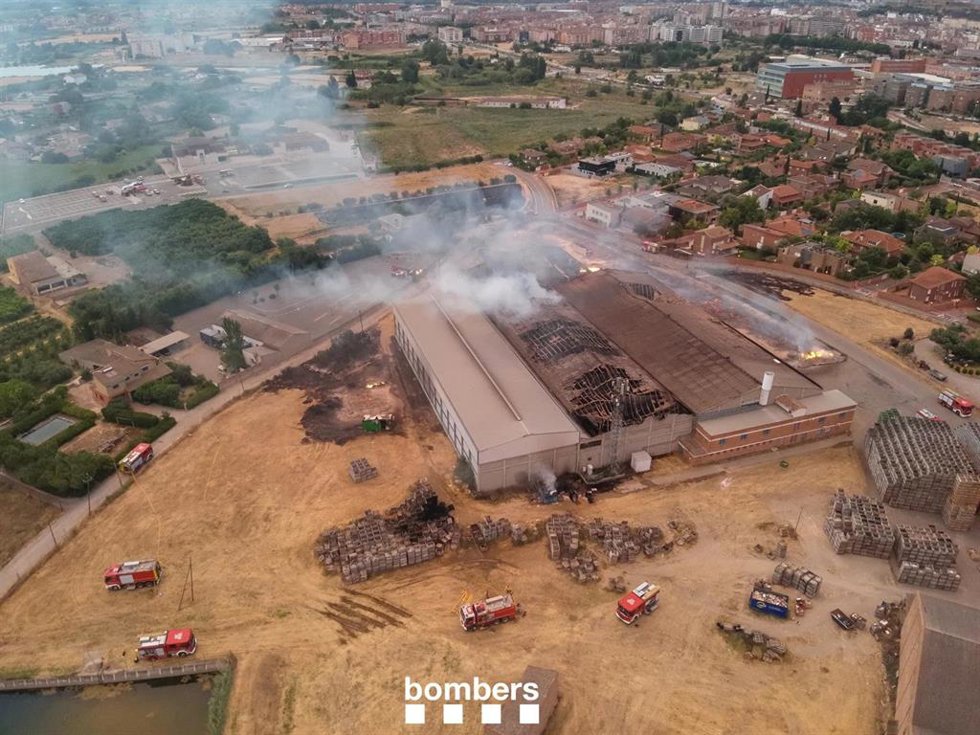 Los Bombers de la Generalitat trabajan en la extinción de un incendio que afecta a dos naves en Lleida
