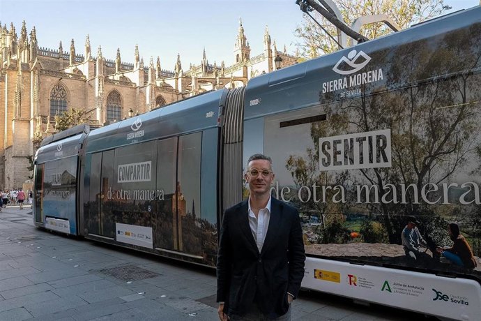 El vicepresidente de Prodetur, Rodrigo Rodríguez Hans, junto un tranvía vinilado con la campaña de promocion turística de la Sierra Morena de Sevilla