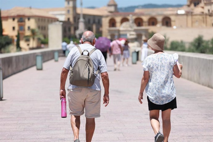 Personas caminando por el Puente Romano de Córdoba bajo el calor.
