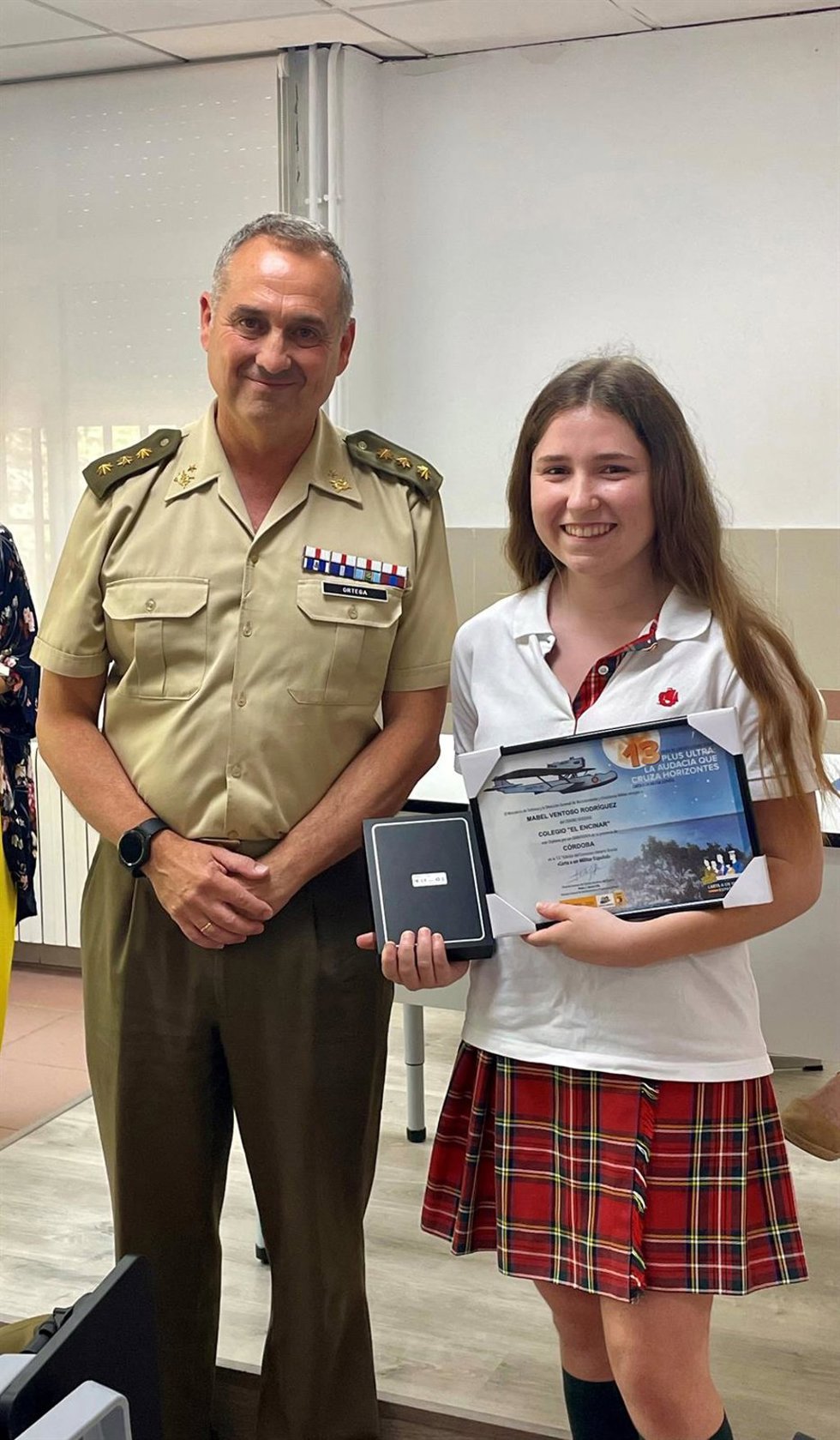 El coronel Ortega con la alumna ganadora del certamen literario escolar.