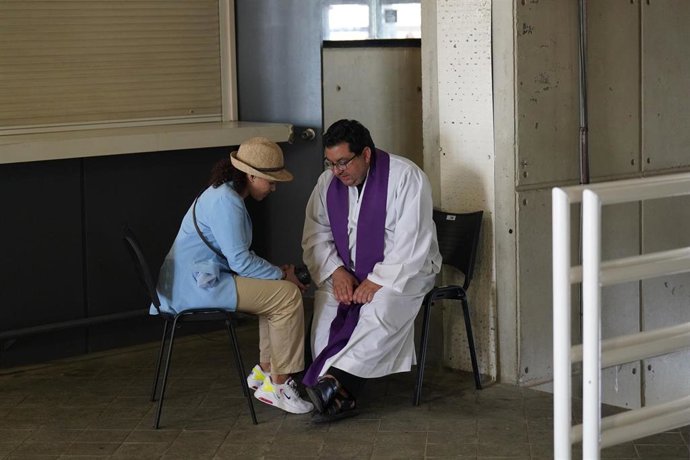 Un sacerdote confiesa a una persona antes de la vigilia de oración con el Papa León XIV, en el Estadio Olímpico Lluís Companys.