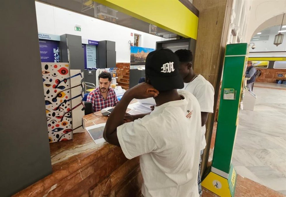 Personas migrantes presentando la solicitud de regularización en una oficia de Correos.
