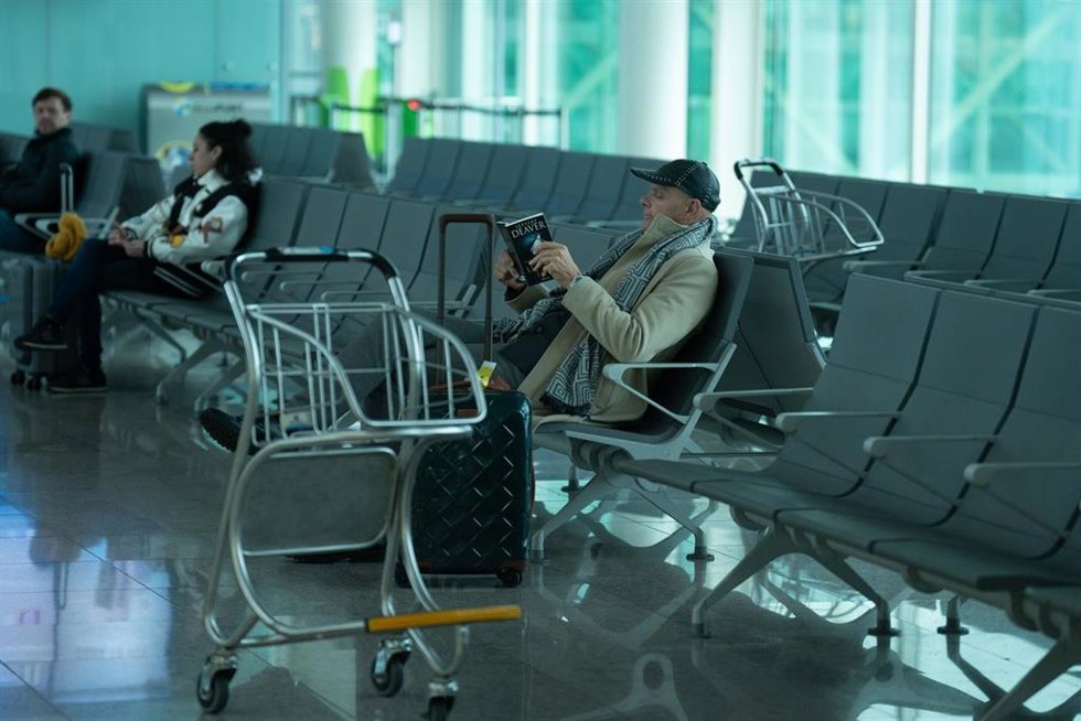 Archivo - Un hombre lee sentado en un aeropuerto.