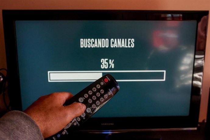 Archivo - Una persona utiliza su mando de la televisión para buscar canales, en Madrid (España), a 7 de octubre de 2020. El cese de emisiones de algunos canales en sus antiguas frecuencias de la TDT en la Comunidad de Madrid se producirá este miércoles, s