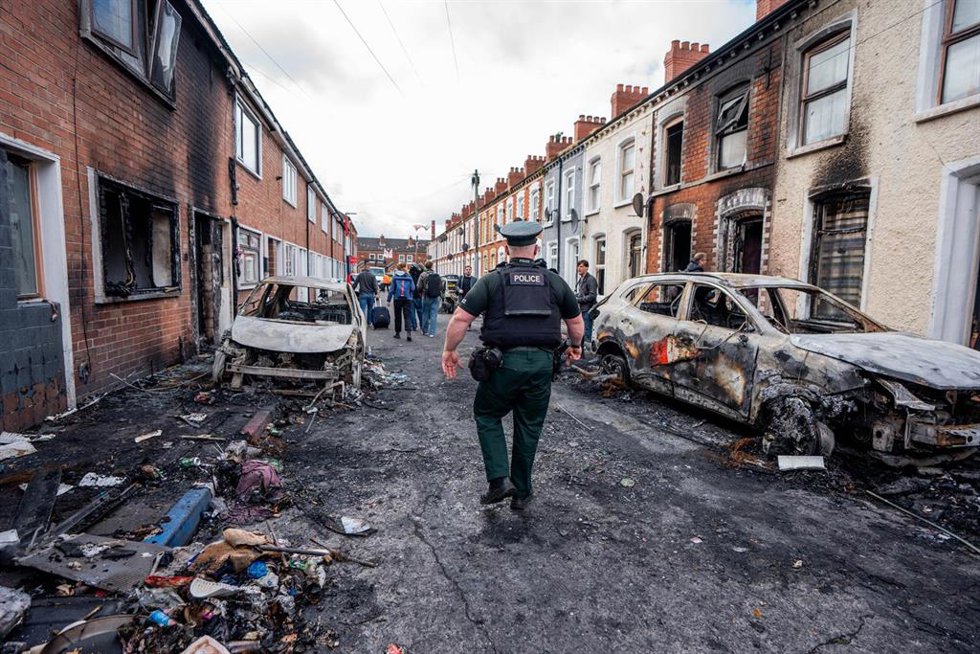 Agente de policía inspeccionando coches y edificios calcinados en la zona de Templemore tras las protestas violentas por el apuñalamiento de un hombre de Belfast Norte. 