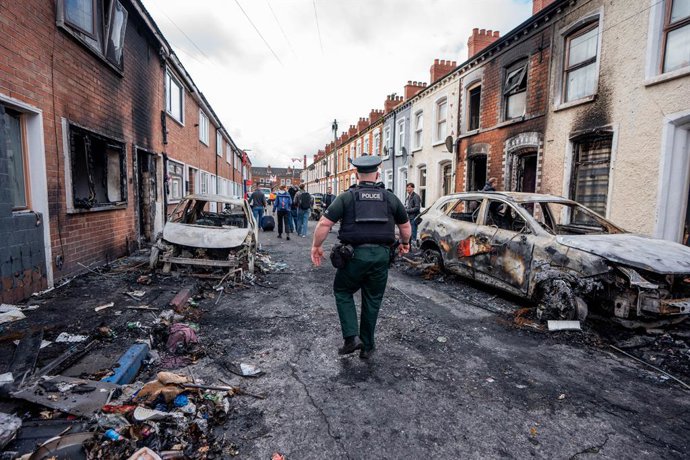 10 de junho de 2026, Belfast, Reino Unido: O policial é visto inspecionando carros e prédios incendiados na área de Templemore. A cidade ficou em chamas quando os moradores saíram às ruas para protestar contra o esfaqueamento de um homem de Belfast do Nor