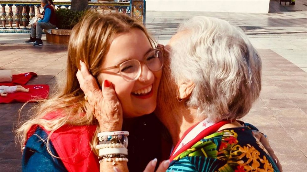 Una mujer mayor junto a una voluntaria de Cruz Roja.