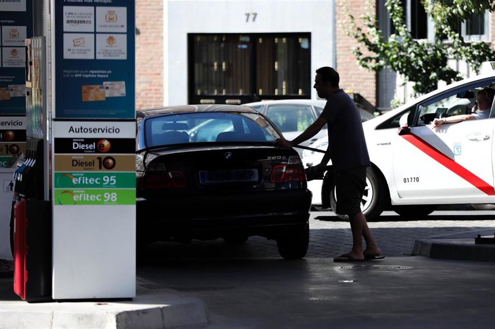 Archivo - Personas ponen gasolina en sus coches en una gasolinera de Madrid.