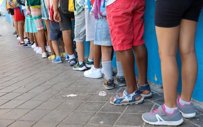 Archivo - Varios niños hacen fila con sus mochilas.  Imagen de archivo.