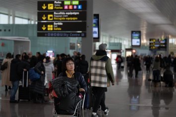 Archivo - Una mujer transporta en un carro sus maletas en el aeropuerto de El Prat, a 19 de enero de 2023