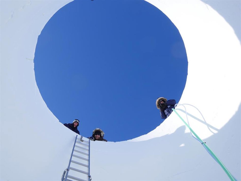 Investigadores asomados al núcleo de hielo analizado.
