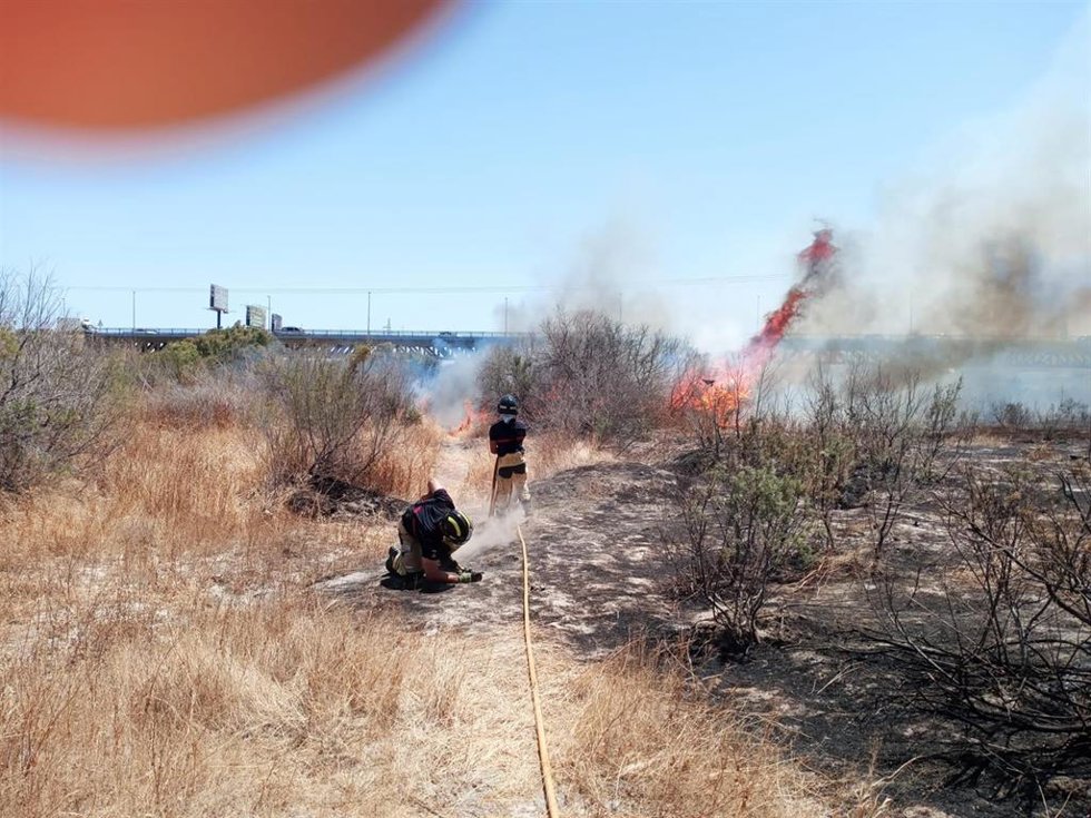Bomberos de Almería trabajan en la extinción del incendio declarado en el cauce del río Andarax, junto al barrio de El Puche.
