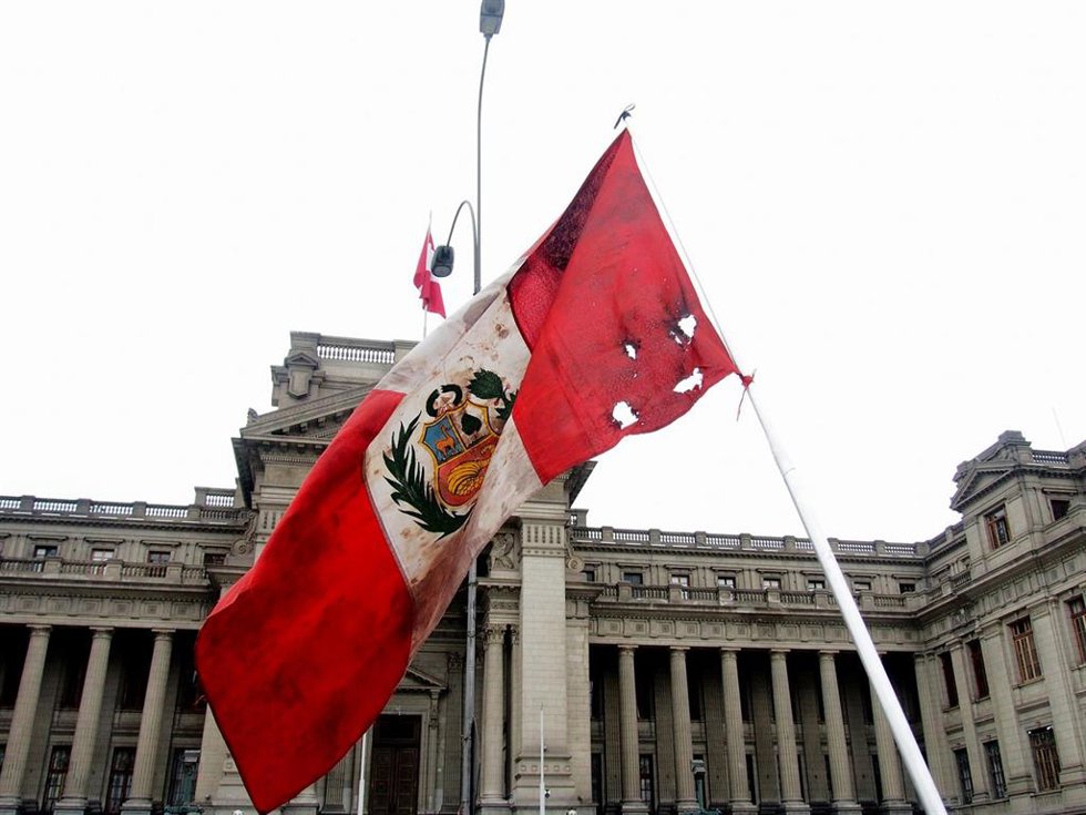 Archivo - Bandera de Perú frente a la fachada del Palacio de Justicia en Lima