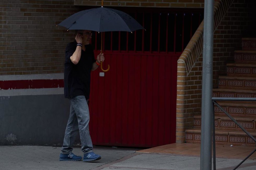 Archivo - Un hombre se protege de la lluvia con un paraguas.
