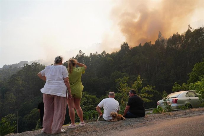 Varias persoas observan un incendio, a 13 de xuño de 2026, en Padrón, A Coruña, Galicia (España).