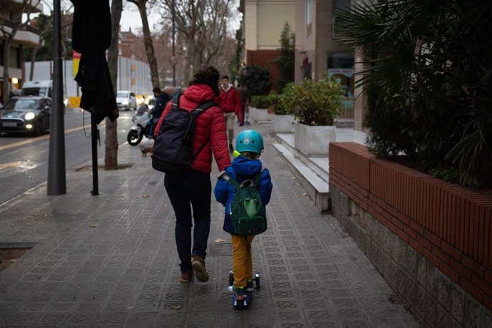 Archivo - Una mujer lleva de la mano a un niño.