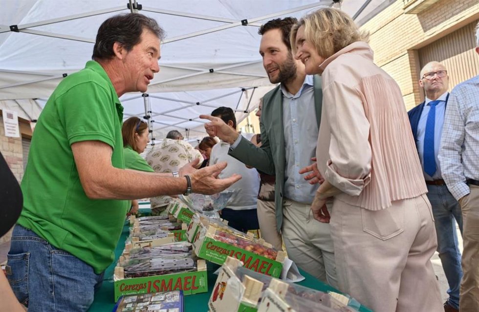 El presidente de la DPH, Isaac CLaver,  y la alcaldesa de La Sotonera, Maribel Bailo, dialogan con un vendedor en uno de los puestos de la Feria de la Cerza de Bolea.