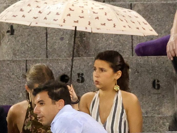 Cayetana Rivera protegiéndose del chaparrón bajo un paraguas durante la corrida de Roca Rey en Las Ventas este domingo