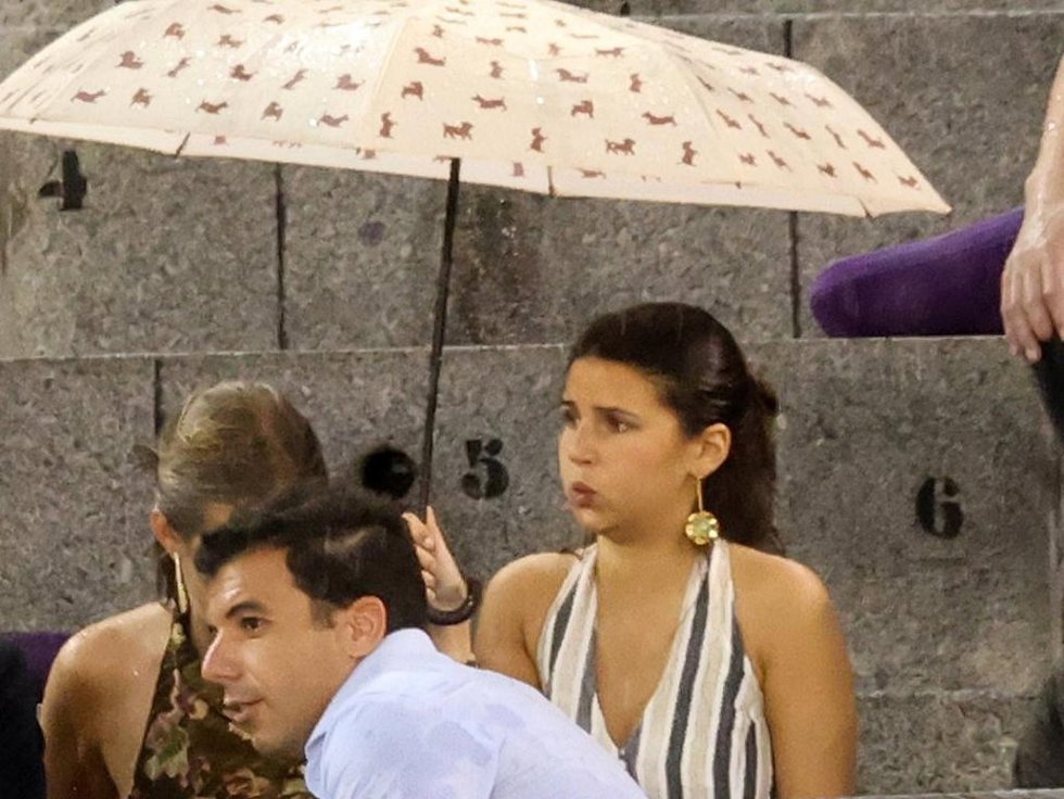 Cayetana Rivera protegiéndose del chaparrón bajo un paraguas durante la corrida de Roca Rey en Las Ventas este domingo