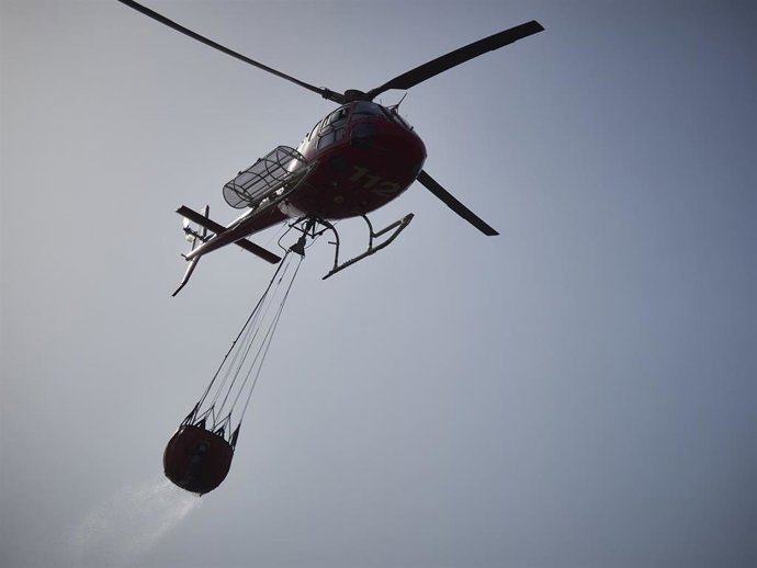 Archivo - Un helicóptero lanza agua para sofocar un incendio en una imagen de archivo.