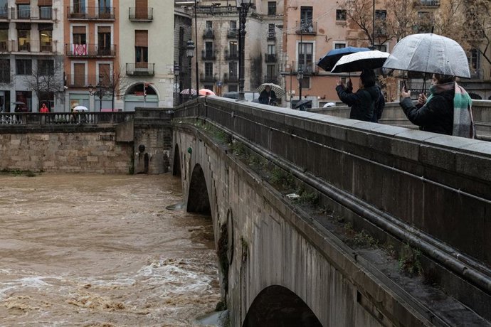 Archivo - Varias personas observan la crecida del río Onyar, a su paso por el centro de la ciudad, a 20 de enero de 2026, en Girona, Catalunya (España)