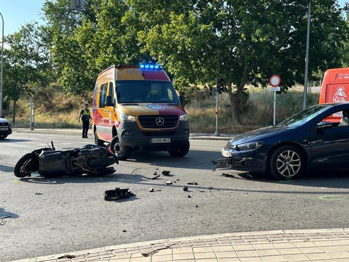 Moto y turismo tras colisionar en un cruce en el distrito madrileño de Latina, junto a una ambulancia de Samu-Protección Civil.