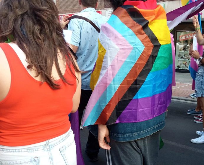 Archivo - Un joven se cubre con una bandera LGTBIQ+ durante una manifestación.