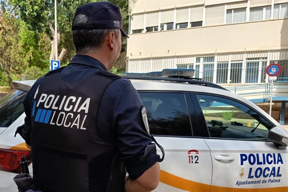 Archivo - Agente de la Policía Local de Palma frente a un coche patrulla