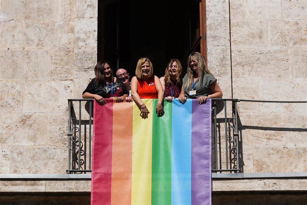 La delegada del Gobierno, Pilar Bernabé (c), despliega la bandera LGTBI+ en la fachada de la Delegación del Gobierno en la Comunitat Valenciana, en el Palacio del Temple, a 17 de junio de 2026, Valencia