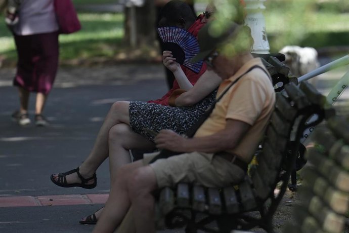 Varias personas se resguardan en la sombra en un parque