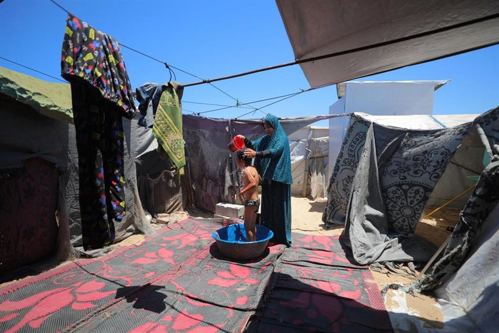 Una madre palestina baña a su hijo en un campamento de desplazados en Al Zauaida, en el centro de la Franja de Gaza (archivo)