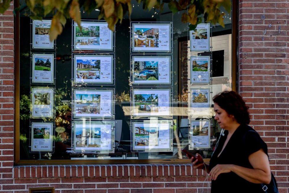 Archivo - Una mujer camina frente a un escaparate de anuncios de viviendas, a 4 de agosto de 2023, en Madrid (España). La compraventa de vivienda en España disminuye un 6,4% interanual por el retroceso de las operaciones sobre los inmuebles usados, según 