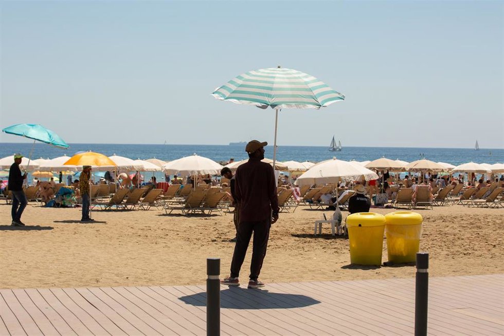 Archivo - Varias personas se protegen del sol en la playa de la Barceloneta, en Barcelona, en una imagen de archivo