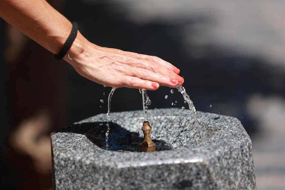 Una persona se refresca la mano en una fuente