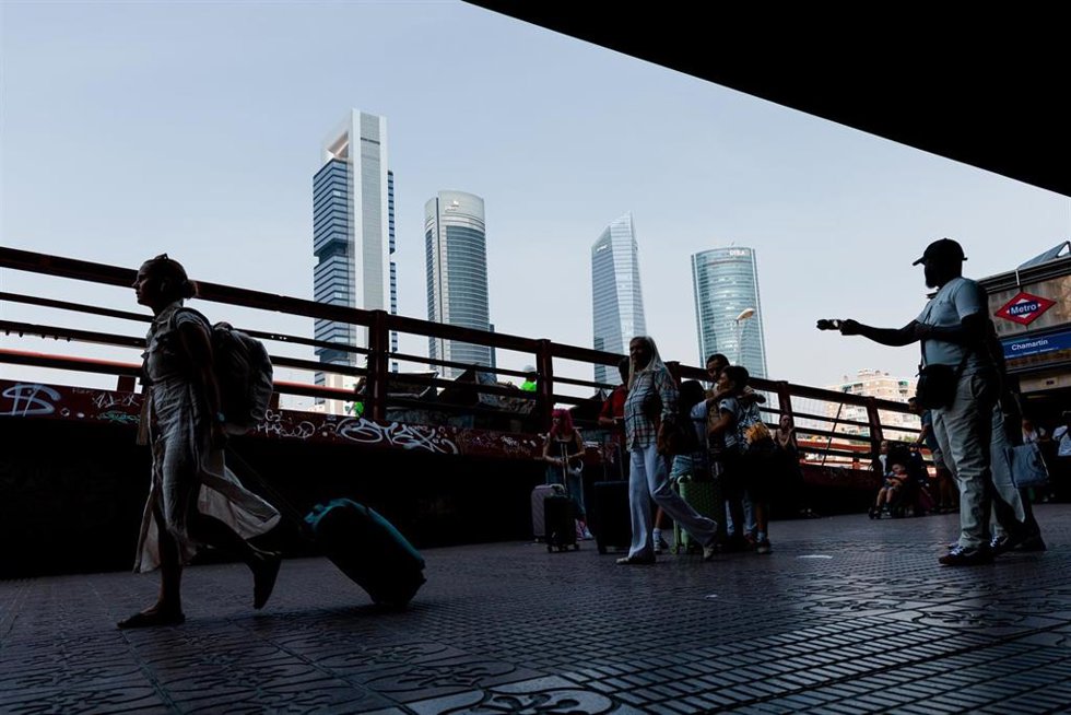 Archivo - Varias personas esperan con maletas en la estación Chamartín Clara Campoamor, con las cuatro torres de fondo