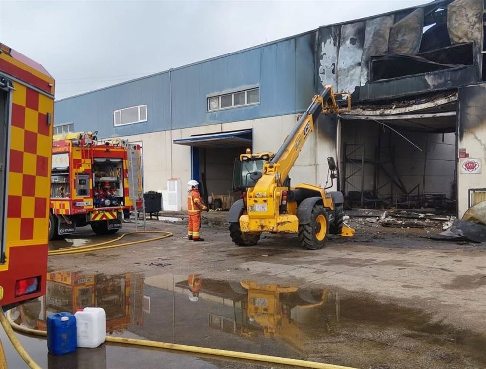 Bomberos trabajan en la extinción de un incendio en una nave industrial de San Juan del Puerto (Huelva).